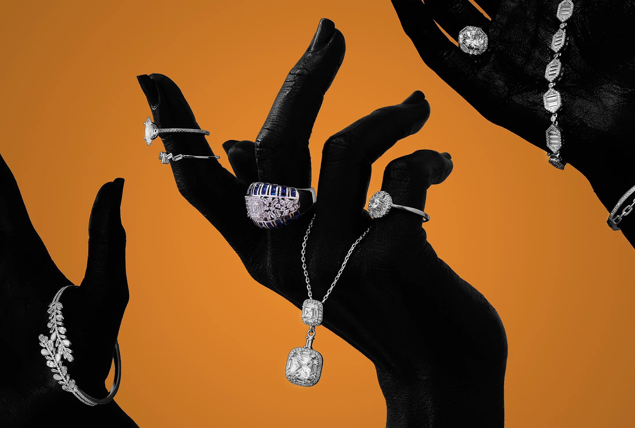 Jewellery suspended between gloved hands against an amber backdrop